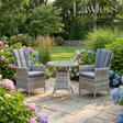 Outdoor garden furniture patio set with two chairs and a table surrounded by flowers and greenery.