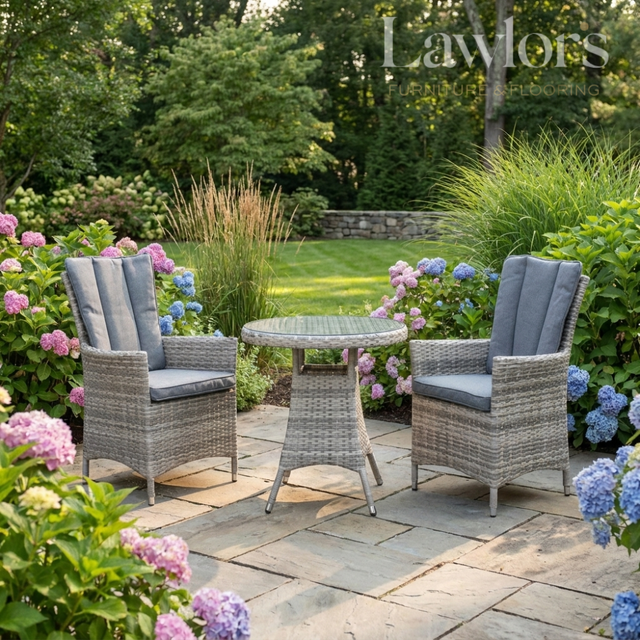 Outdoor garden furniture patio set with two chairs and a table surrounded by flowers and greenery.