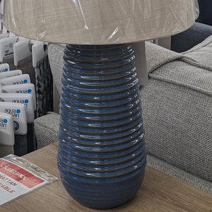 The Ridge Blue Ceramic Table Lamp 58cm features a circular textured base and cream shade with a 58cm tall lamp that adds style and warmth to any room