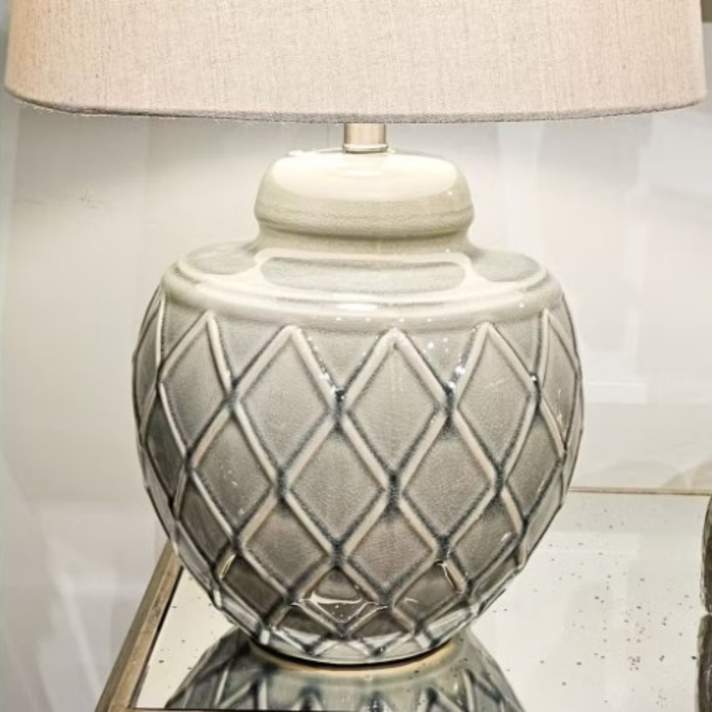 The Rina Ceramic Table Lamp features a green geometric ceramic base and beige fabric shade, a modern design that adds elegance and warmth