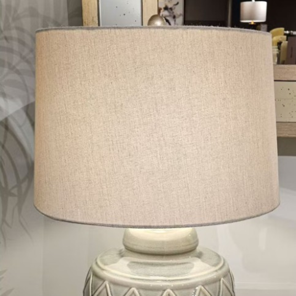 The Rina Ceramic Table Lamp features a green geometric ceramic base and beige fabric shade, a modern design that adds elegance and warmth