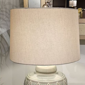 The Rina Ceramic Table Lamp features a green geometric ceramic base and beige fabric shade, a modern design that adds elegance and warmth
