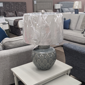 The Rina Ceramic Table Lamp features a green geometric ceramic base and beige fabric shade, a modern design that adds elegance and warmth