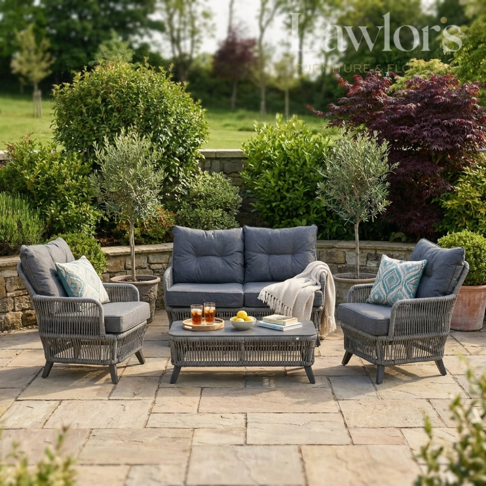 Outdoor garden furniture patio set with gray cushions and a stone patio.