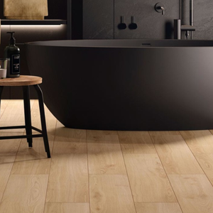 Light natural wood plank flooring in a modern bathroom setting with a matte black freestanding bathtub and dark wall fixtures.