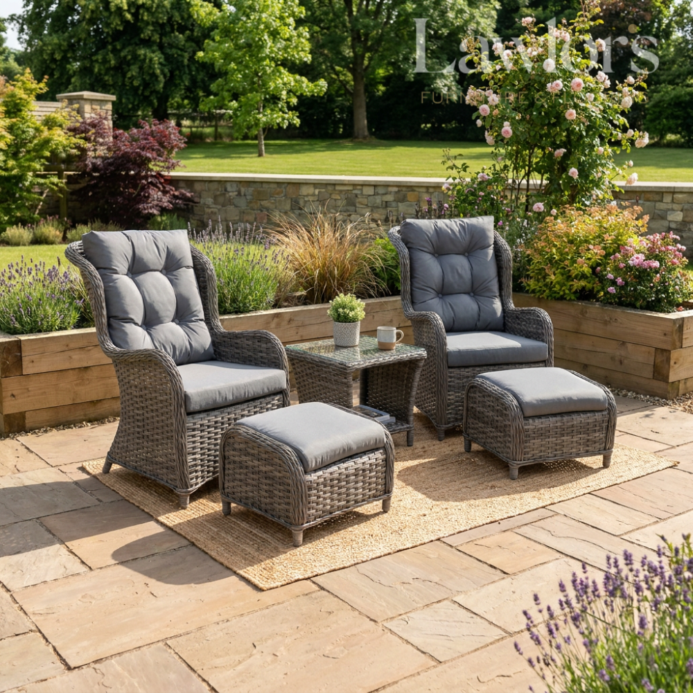 Outdoor garden furniture patio set with two chairs, ottomans, and a table on a stone patio with garden background.