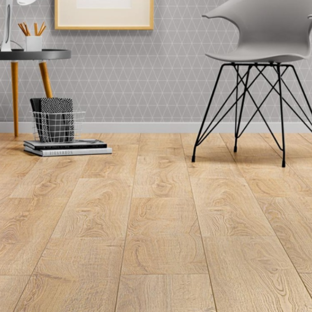 Light oak wood plank flooring shown in a modern room setting with a gray chair, desk, and patterned wallpaper.