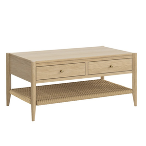 A mid-century modern coffee table made of light natural wood with two drawers and a woven rattan lower shelf, shown on a plain white background.