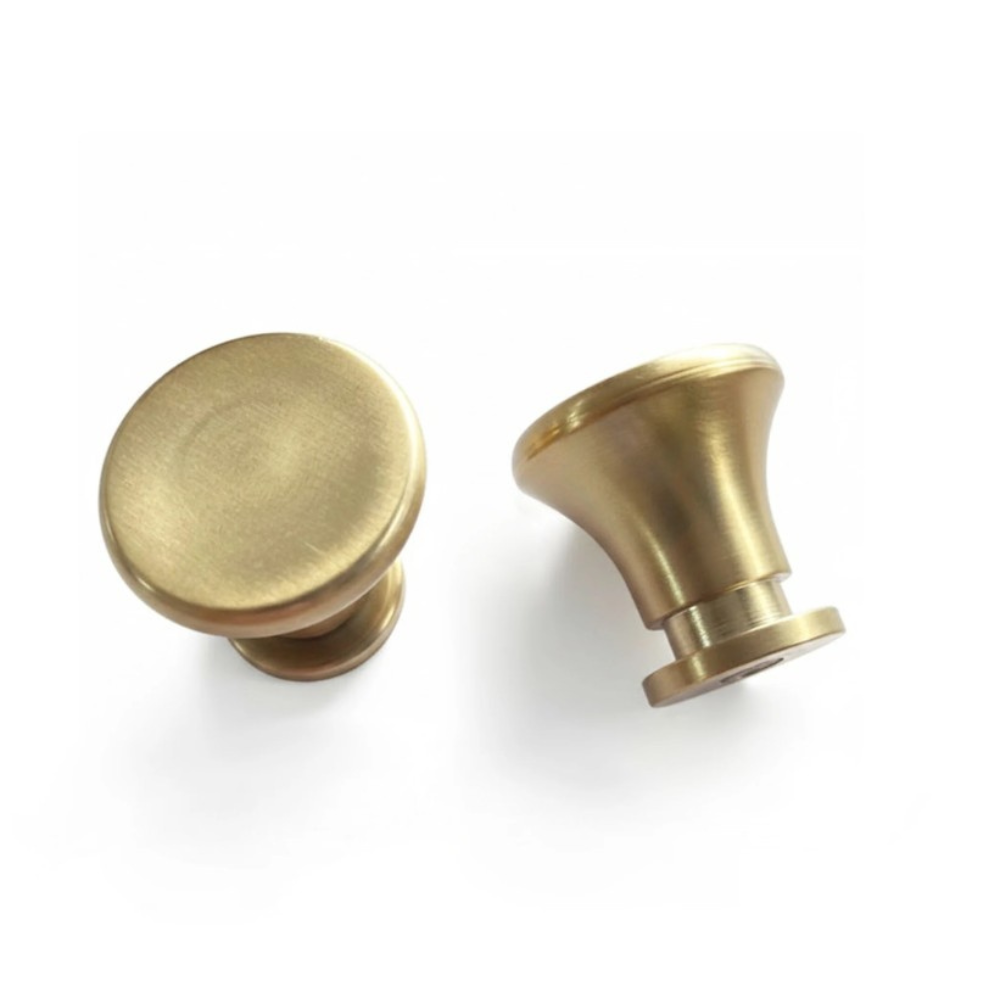 Two brass cabinet knobs, one round and one conical, shown on a clean white background.