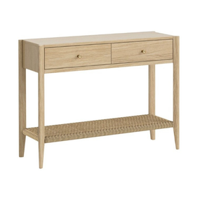 A light oak wood console table with two drawers, small brass knobs, and a woven rattan lower shelf, shown on a plain white background.