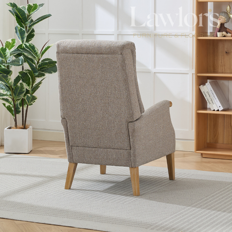 Beige upholstered chair in a room with a plant and bookshelf.