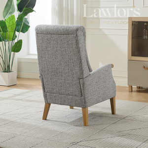 Grey upholstered armchair in a room with a plant and furniture.