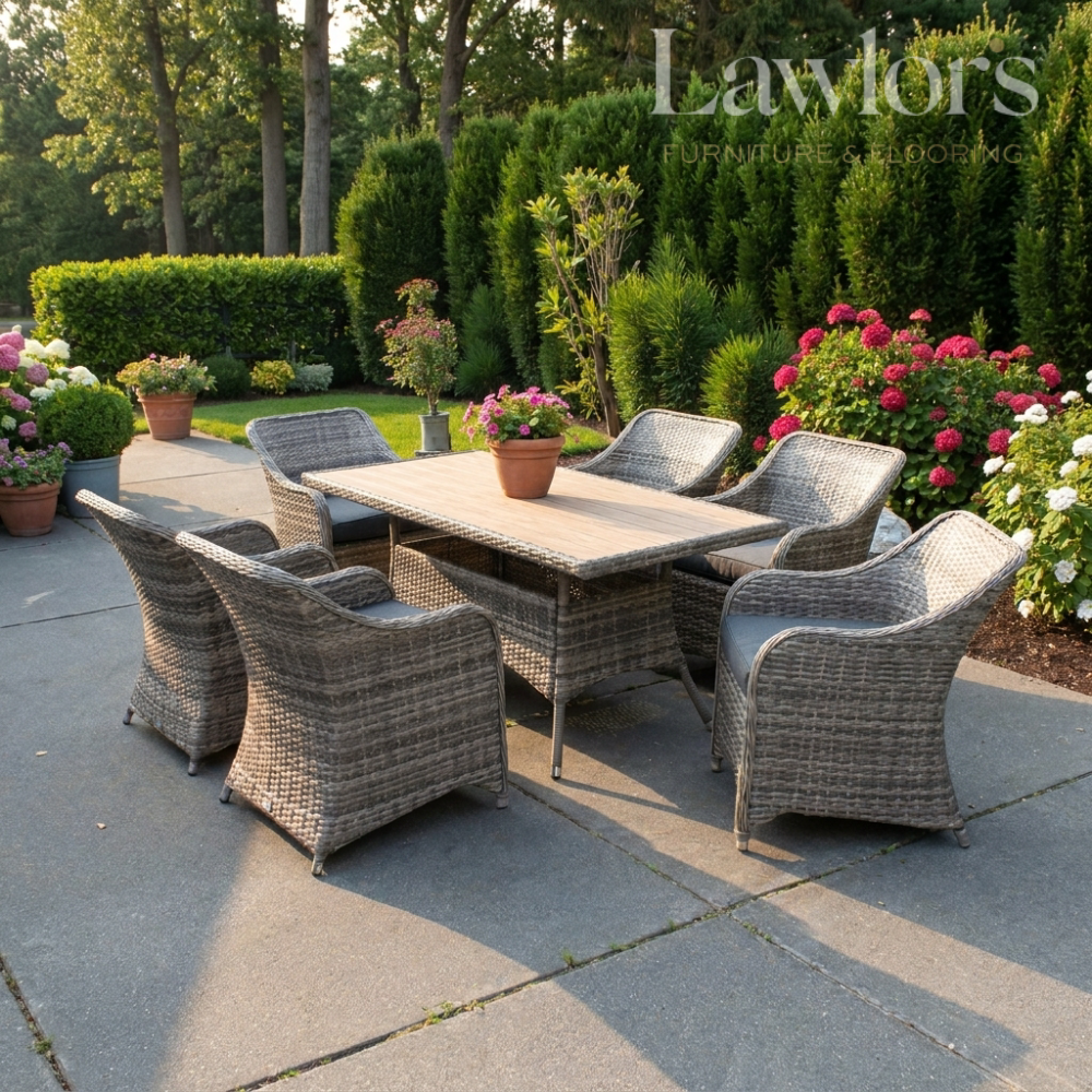 Outdoor garden furniture patio set with table and chairs on a stone patio, surrounded by greenery and flowers.