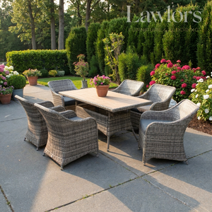 Outdoor garden furniture patio set with table and chairs on a stone patio, surrounded by greenery and flowers.