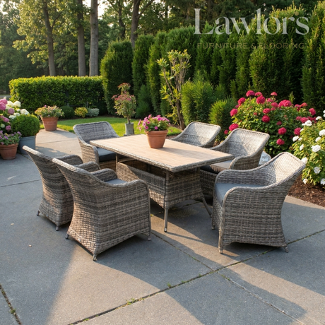Outdoor garden furniture patio set with table and chairs on a stone patio, surrounded by greenery and flowers.