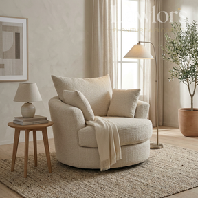 Beige swivel armchair in a living room with a side table, lamp, and plant.