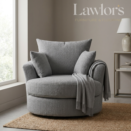 Grey swivel armchair with cushions and a blanket in a room with a lamp and window.