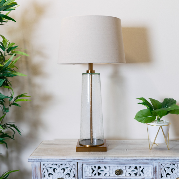 The elegant Amara Table Lamp Bubble Glass features a distinctive slanted base crafted from bubbled glass and brass fitting